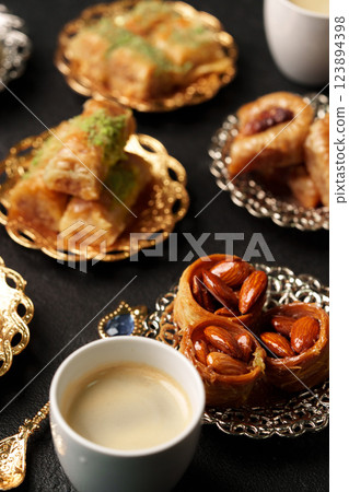 Traditional Middle Eastern sweets and coffee presented on ornate dishes during a festive gathering Traditional Middle Eastern sweets and coffee presented on ornate dishes during a festive gathering 123894398