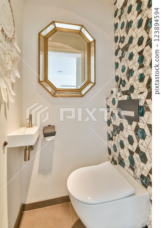 A beautifully designed bathroom showcasing a stylish sink, a gold-framed mirror, and geometric tiles enhancing the modern aesthetic. A beautifully designed bathroom showcasing a stylish sink, a gold-framed mirror, and geometric tiles enhancing the modern aesthetic. 123894594