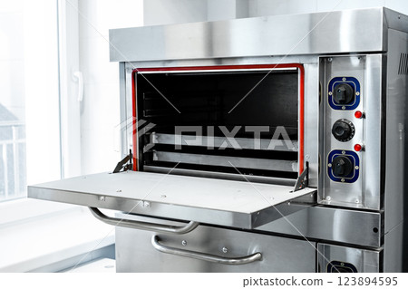 Industrial baking oven with open door and visible interior racks in a modern kitchen environment Industrial baking oven with open door and visible interior racks in a modern kitchen environment 123894595