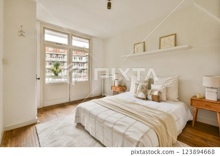 A serene bedroom featuring a light color palette, wooden flooring, and minimalist furniture, creating a calming atmosphere perfect for relaxation. 123894668
