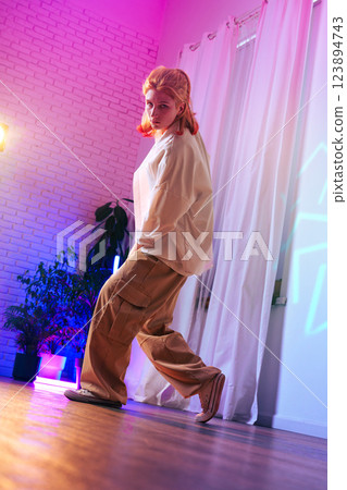 Young dancer performs contemporary movement in a vibrant studio with colorful lighting and expressive ambiance 123894743