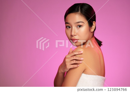 Model showcasing beauty and skincare in a studio with pink lighting during a photoshoot session 123894766