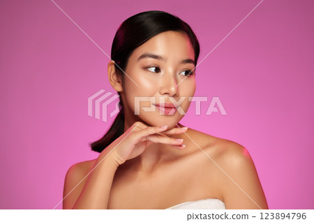 Elegant model posing gracefully against a vibrant pink backdrop showcasing beauty and confidence 123894796