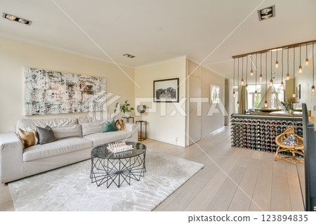 A stylish modern living room featuring soft furnishings, contemporary art, and a cozy atmosphere complemented by ambient lighting and minimalistic design. 123894835