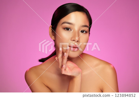 Beautiful model poses gracefully with soft lighting on pink background 123894852