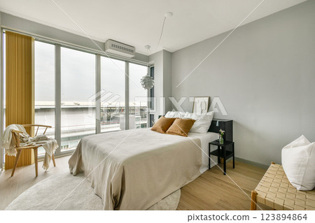 A tranquil modern bedroom featuring soft colors, large windows inviting natural light, and stylish furnishings, creating a relaxing atmosphere. A tranquil modern bedroom featuring soft colors, large windows inviting natural light, and stylish furnishings, creating a relaxing atmosphere. 123894864