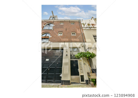 A photo displaying the intricately designed facade of a building featuring brick and modern elements, complemented by greenery. The unique architecture captivates the eye. 123894908