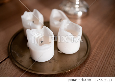 Melted white candles on brass tray with wooden surface background Melted white candles on brass tray with wooden surface background 123894945