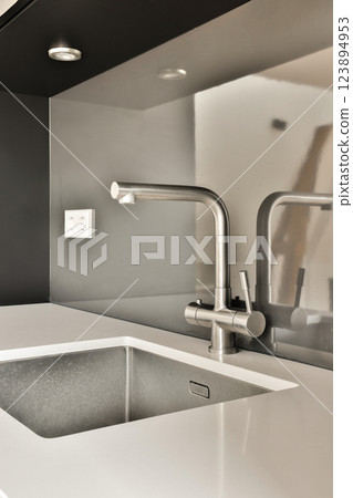 A contemporary kitchen sink featuring a minimalist design, stainless steel finish, and a stylish faucet against a modern backdrop, ideal for contemporary interiors. A contemporary kitchen sink featuring a minimalist design, stainless steel finish, and a stylish faucet against a modern backdrop, ideal for contemporary interiors. 123894953