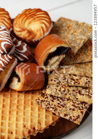Assortment of sweet pastries and crispy snacks arranged on a wooden platter Assortment of sweet pastries and crispy snacks arranged on a wooden platter 123894957