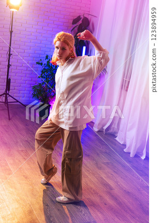 Confident dancer showcasing moves in a brightly lit studio during an evening practice session Confident dancer showcasing moves in a brightly lit studio during an evening practice session 123894959