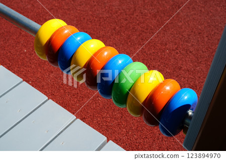 Colorful wooden counting beads shine in sunlight on a playground equipment during daytime outdoor playtime 123894970