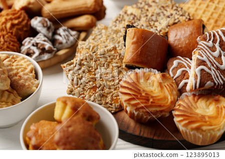 Assortment of baked treats displayed on wooden platter and bowls at a dessert gathering in a cozy setting 123895013