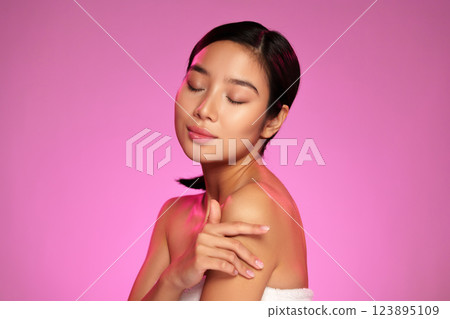 Portrait of a woman enjoying a moment of calm with closed eyes in a vibrant pink background 123895109