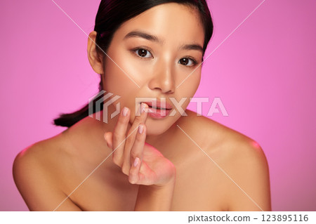 Model poses gracefully against a vibrant pink backdrop showcasing natural beauty and delicate features 123895116