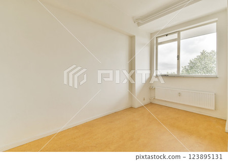 A minimalist empty room featuring a large window that offers a view of greenery outside, highlighting the simplicity and spaciousness of the space. 123895131