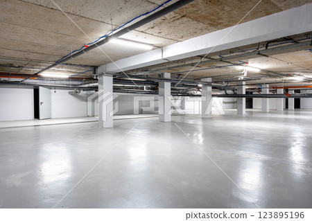 Spacious underground parking area featuring modern design and clean aesthetics in an urban location 123895196