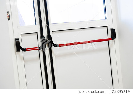 Red handle door assembly at a modern building entrance for easy accessibility and safety during daily use Red handle door assembly at a modern building entrance for easy accessibility and safety during daily use 123895219