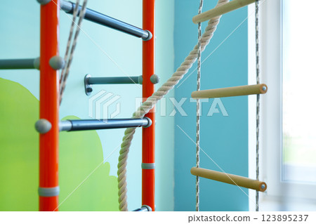 Climbing structure with ropes and bars in a colorful indoor play area for children Climbing structure with ropes and bars in a colorful indoor play area for children 123895237