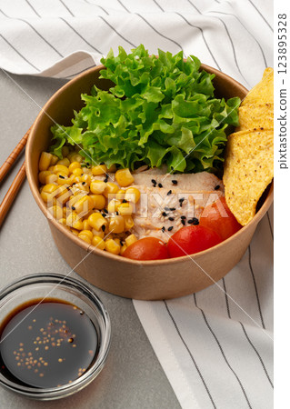 Fresh salad bowl with lettuce, corn, tomatoes, grilled chicken, and tortilla chips served with dipping sauce 123895328