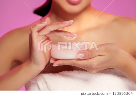 Woman applying cream during a skincare routine in a bright indoor setting Woman applying cream during a skincare routine in a bright indoor setting 123895364