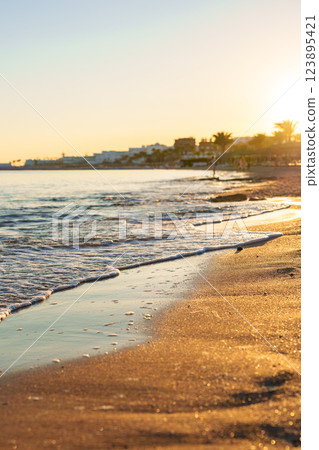 Serene sunset over tranquil beach with gentle waves lapping the shore in a coastal town during golden hour Serene sunset over tranquil beach with gentle waves lapping the shore in a coastal town during golden hour 123895421