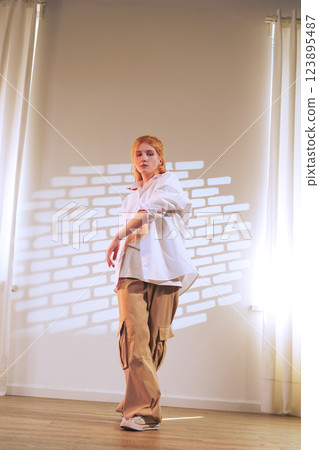 Dancer showcasing expressive movements in a bright studio with natural light filtering through sheer curtains 123895487