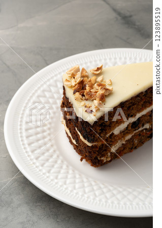 Delicious layered cake topped with cream and nuts placed on a white decorative plate 123895519