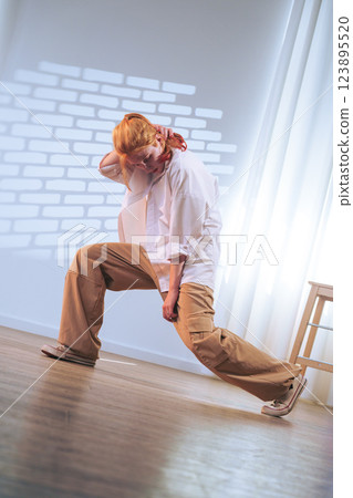Young dancer performs dynamic move in bright studio space during daytime practice session 123895520