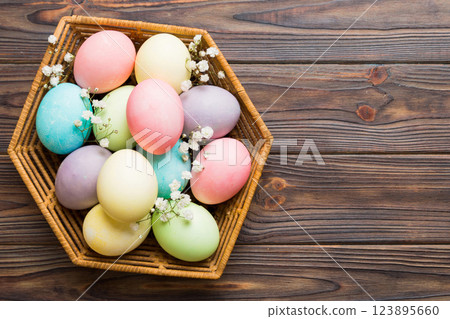 Happy Easter composition. Easter eggs in basket on colored table with gypsophila. Natural dyed colorful eggs background top view with copy space Happy Easter composition. Easter eggs in basket on colored table with gypsophila. Natural dyed colorful eggs background top view with copy space 123895660