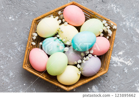 Happy Easter composition. Easter eggs in basket on colored table with gypsophila. Natural dyed colorful eggs background top view with copy space 123895662