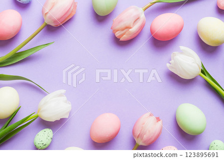 Happy Easter composition. Easter eggs on colored table with yellow Tulips. Natural dyed colorful eggs background top view with copy space Happy Easter composition. Easter eggs on colored table with yellow Tulips. Natural dyed colorful eggs background top view with copy space 123895691