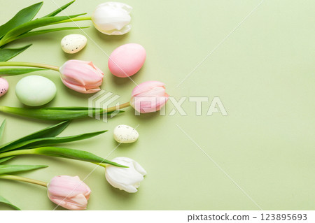 Happy Easter composition. Easter eggs on colored table with yellow Tulips. Natural dyed colorful eggs background top view with copy space 123895693