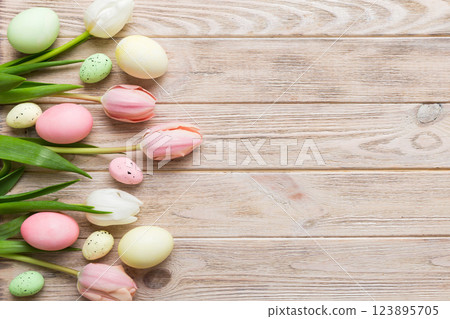 Happy Easter composition. Easter eggs on colored table with yellow Tulips. Natural dyed colorful eggs background top view with copy space 123895705