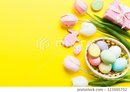 Easter frame with eggs, gift box and tulip on a colored background. The minimal concept. Top view Happy Easter composition. Card with a copy space of the place for the text Easter frame with eggs, gift box and tulip on a colored background. The minimal concept. Top view Happy Easter composition. Card with a copy space of the place for the text 123895732