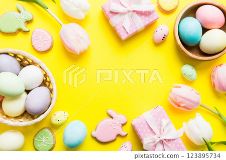 Easter frame with eggs, gift box and tulip on a colored background. The minimal concept. Top view Happy Easter composition. Card with a copy space of the place for the text 123895734