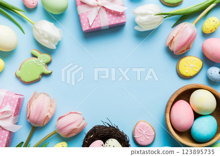 Easter frame with eggs, gift box and tulip on a colored background. The minimal concept. Top view Happy Easter composition. Card with a copy space of the place for the text 123895735