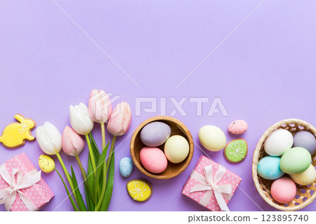 Easter frame with eggs, gift box and tulip on a colored background. The minimal concept. Top view Happy Easter composition. Card with a copy space of the place for the text Easter frame with eggs, gift box and tulip on a colored background. The minimal concept. Top view Happy Easter composition. Card with a copy space of the place for the text 123895740