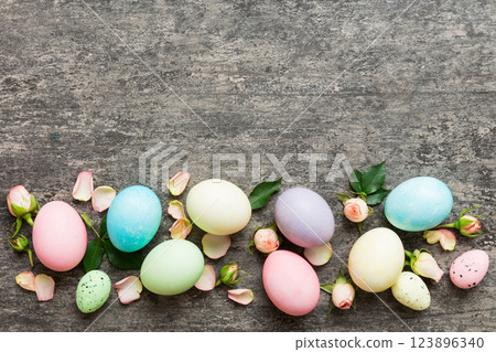 Happy Easter. Easter eggs on colored table with yellow roses. Natural dyed colorful eggs background top view with copy space 123896340