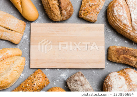 Minimalist wooden cutting board blank mockup on background of Types of homemade bread. Different kinds of fresh bread as background, top view with space for your text or design Minimalist wooden cutting board blank mockup on background of Types of homemade bread. Different kinds of fresh bread as background, top view with space for your text or design 123896694