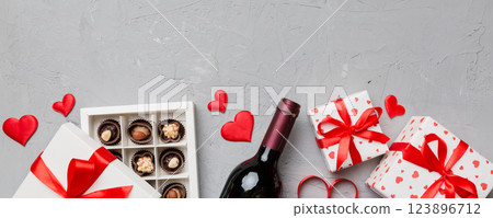 Bottle of red wine on colored background for Valentine Day with gift and chocolate. Heart shaped with gift box of chocolates top view with copy space Bottle of red wine on colored background for Valentine Day with gift and chocolate. Heart shaped with gift box of chocolates top view with copy space 123896712