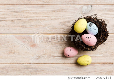Colorful easter eggs in nest on table background with copy space top view 123897171