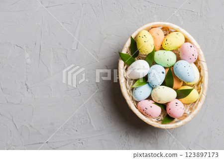 Colorful Easter eggs in wicker basket against colored background, closeup. top view with copy space Colorful Easter eggs in wicker basket against colored background, closeup. top view with copy space 123897173