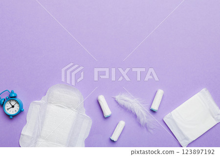 Ringing alarm clock with sanitary female tampons and menstrual sanitary pads. Medical concept of woman critical days and menstruation. Female daily hygiene. Copy space Ringing alarm clock with sanitary female tampons and menstrual sanitary pads. Medical concept of woman critical days and menstruation. Female daily hygiene. Copy space 123897192