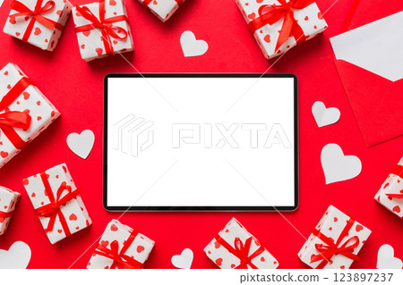 Top view of digital tablet with gift boxes and hearts on colorful background. Tablet with black screen with Holiday decorations gift box top view 123897237