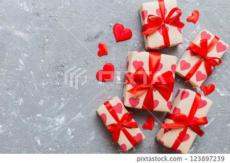 Top view photo of valentine day decorations gift box with red ribbon bow on colored background. Holiday gift boxes with top view Top view photo of valentine day decorations gift box with red ribbon bow on colored background. Holiday gift boxes with top view 123897239