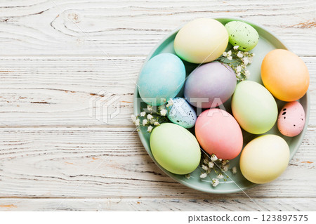 Happy Easter composition. Easter eggs in basket on colored table with gypsophila. Natural dyed colorful eggs background top view with copy space 123897575