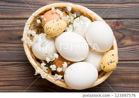 Happy Easter composition. Easter eggs in basket on colored table with gypsophila. Natural dyed colorful eggs background top view with copy space 123897576