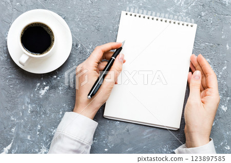 Woman hand with pencil writing on notebook and hold coffee cup. Woman working on office table with coffee 123897585