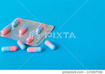 Medicine pills on a light background. Medicines and prescription pills flat lay background. Blue and pink medical tablets in blister 123897586